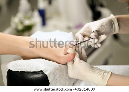 Close up Cutting cuticle on foot, nail scissors. On backgroun of flower and equipment for Pedicure process
