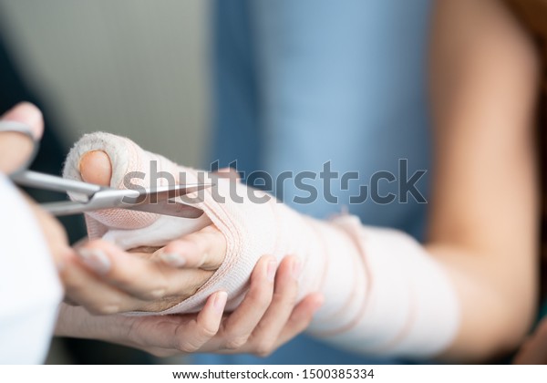 Close up of cutting splint plaster cast from\
woman patient arm using sharp scissor as hospital care center.\
Trauma can happen after people fall and hurt physically from\
accidents. Rehab center\
service