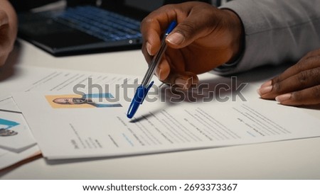 Close up of CV document evaluation in a corporate job interview, businesswoman asking african american candidate questions based on his past work experience and studies shown on paper. Camera B.