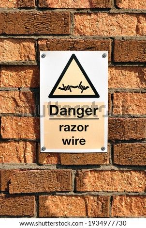 Close Up of 'Danger Razor Wire' Sign on Old Brick Wall