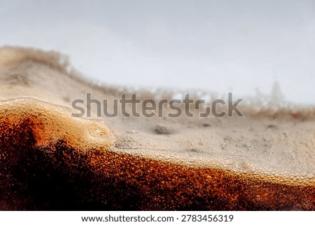 Close up of dark cola splashing with bubbles and droplet on white background. Dynamic liquid wave texture, refreshing soda macro shot for commercial use, beverage advertising abstract concept