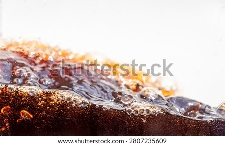 Close up of dark cola splashing with bubbles and droplet on white background. Dynamic liquid wave texture, refreshing soda macro shot for commercial use, beverage advertising abstract concept