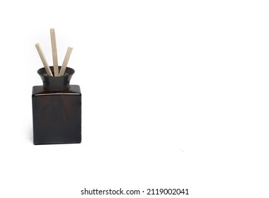 Close Up Of Dark Glass Container With Wooden Sticks In It To Put As Room Fragrance And To Improve Air On White Background