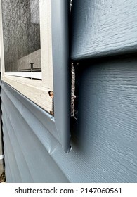 Close Up Of A Dark Pacific Blue Newly Vinyl Sided Home Window Frame With Damage And Flashing Foil Exposed.