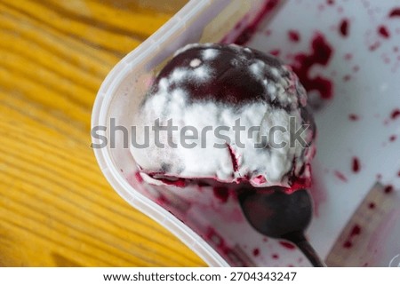 close up of a dark red beetroot covered in white mold inside a plastic container with a spoon, concept of food safety, bacterial spoilage, microbiological risk. 