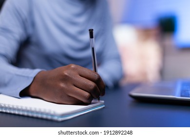 Close up of dark skinned woman taking notes while working from home office sitting at desk comp. Black freelancer respecting deadline studying late at night. - Shutterstock ID 1912892248