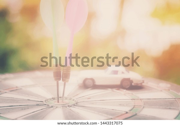 close up dart arrow hitting on target\
center, toy car on dartboard, saving and manage to success\
transport business technology concept, vintage\
tone