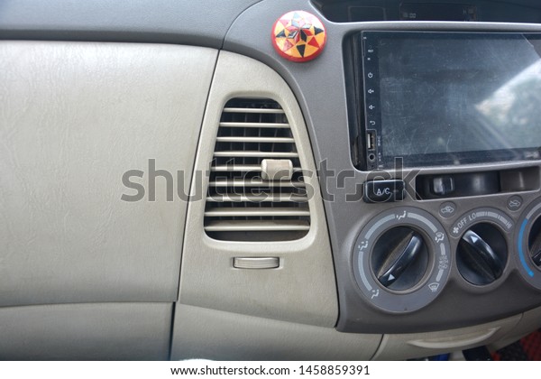 Close up of the dashboard of a car\
with ac air vents / outlets, screen, and ac control knobs\
