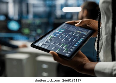 Close up of data center developer running simulations on tablet for AI forecasting, tracking performance. Server hub IT expert using device, integrating artificial intelligence APIs into software