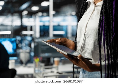 Close up of data center engineer using tablet, deploying and maintaining server and network hardware. Server hub employee using device to manage large scale IT infrastructure