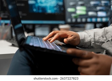 Close up of data center technician using artificial intelligence computerized model on laptop. Server room employee typing on notebook keyboard, using machine learning AI algorithms