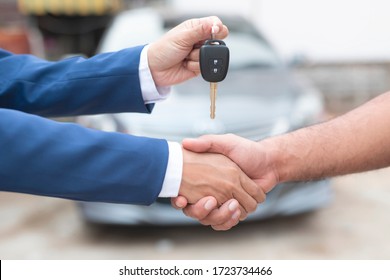 Close up of dealer giving key to new owner and shaking hands in auto show.auto business, car sale, deal,concept - Shutterstock ID 1723734466