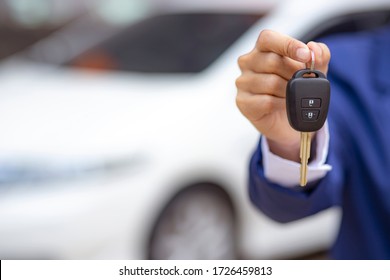 Close up of dealer giving key to new owner and shaking hands in auto show.auto business, car sale, deal,concept - Shutterstock ID 1726459813