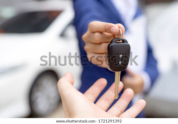 Close up of\
dealer giving key to new owner and shaking hands in auto show.auto\
business, car sale,\
deal,concept