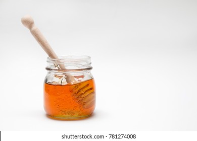 Close up of a decorative honey jar and a honey spoon on a white background with text space