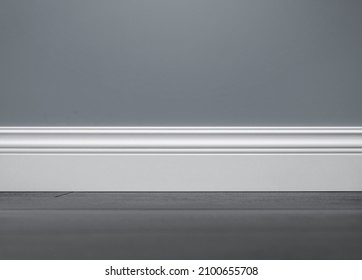 Close up of decorative, moulding white baseboard in empty room with copy space - Shutterstock ID 2100655708