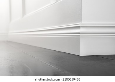 Close up of decorative, moulding white baseboard corner in empty room with copy space - Shutterstock ID 2100659488