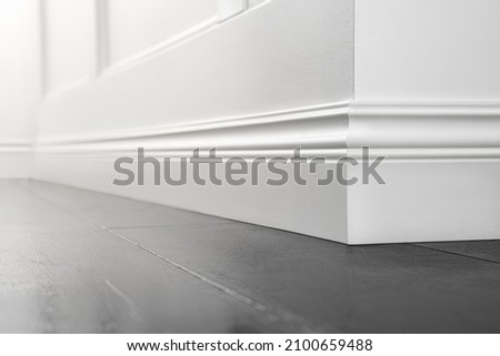 Close up of decorative, moulding white baseboard corner in empty room with copy space