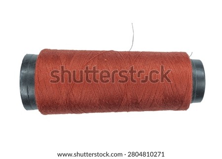 Close up of deep brown sewing thread on black plastic spool. High quality thread used for heavy duty fabric construction garment making and general hobby projects