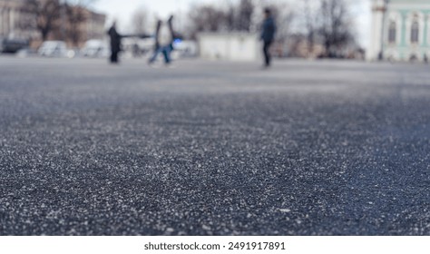 Close up of de-iced asphalt surface with blurred background of people walking in city square. Focus on textured ground with patches of ice melt creating gritty appearance. - Powered by Shutterstock