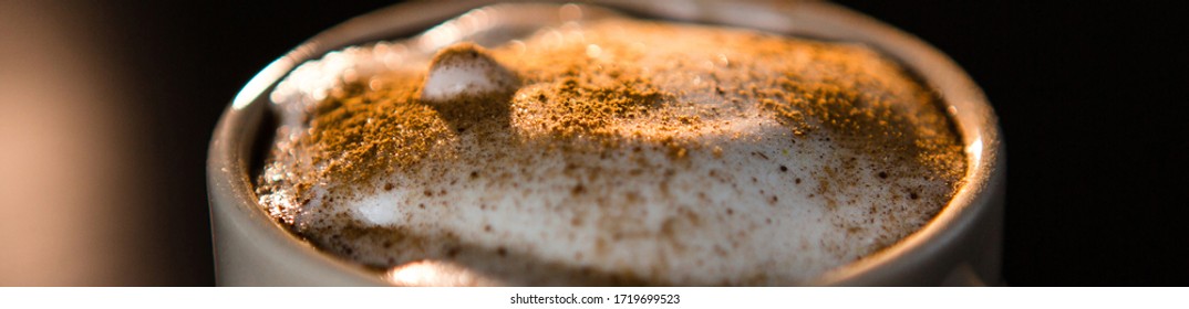 Close Up Of Delicious Cappuccino With Cinnamon And Milk Foam In Cup On Dark Table.