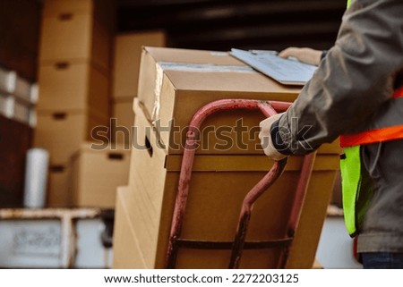 Close up of deliverer unloading cardboard boxes out of a truck. 