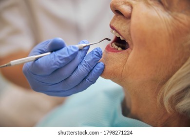 Close up of dentist hand holding metal tools near the face elderly female patient while sitting in the dentist chair in the dental clinic - Shutterstock ID 1798271224