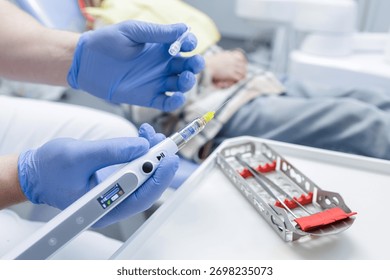 Close up of dentist preparing computer controlled anesthesia syringe with cartridge and needle for local injection in a bright dental clinic.