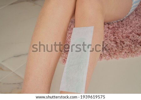 Close up of depilation strips in female hands, woman wants to remove hairs from long slender legs.