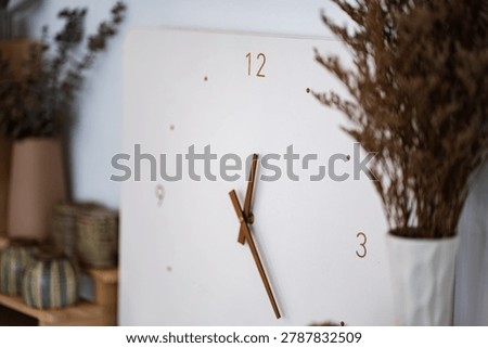 Close up desk with round wall clock, cup and flower in bottle vase on white background. Home office minimal workspace desk