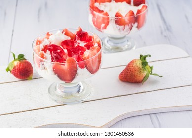 Close up of dessert glass with  lyers of ingredients - angel food loaf pieces, strawberry jello and strawberries with whipped cream.