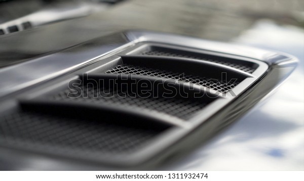 Close up for detail of air vents on the bonnet\
of a modern black car. Stock. Car exterior background detail of air\
intake in hood, design\
concept.