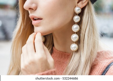 Close up detail of beautiful young blonde woman dressed in pink sweater with gorgeous earrings made of big pearls. 
 - Shutterstock ID 532244686