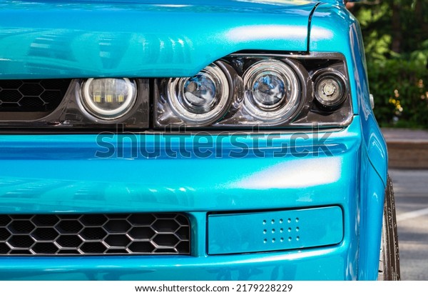 Close up detail blue modern car headlights with\
led technology on gray pavement background with copy space for\
text. shot of headlight. Modern and expensive sport car concept.\
Transport concept