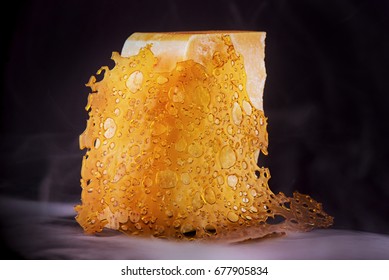 Close up detail of cannabis oil concentrate aka shatter with cheese block isolated over black with smoke - medical marijuana edible concept