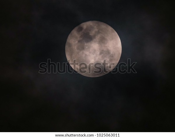 close up the detail of\
full moon with cloudy sky on black background , zoom image with\
telephoto lens