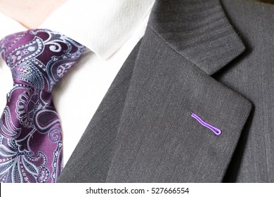 Close up detail image of bespoke tailored grey business suit with purple tie, waistcoat and shirt