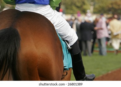 Close Up Detail Of Jockey On Race Horse With Nicely Blurred Crowd Of Fans In Background