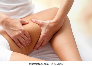 Close Up Detail Of Rehabilitation Massage On Female Thigh.Hands Applying Pressure On Leg. 