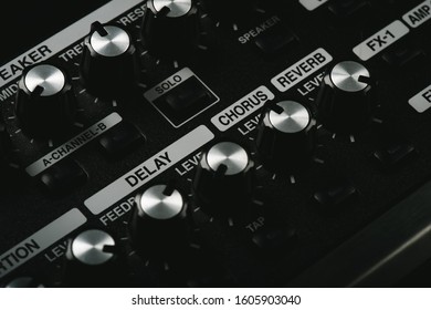 Close up detail of sound equalizer control knobs of a black guitar amplifier. Delay, chours, reverb and distortion knobs.