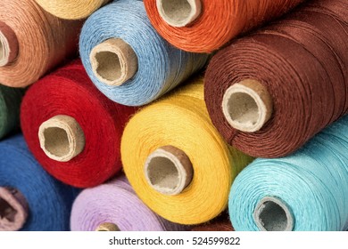 Close up detail still life of colorful red yellow blue multicolored spools of thread isolated on white background copy space - concept fashion DIY clothing sewing handicraft design handmade tradition