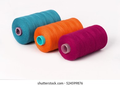 Close up detail still life of cyan orange purple spools of thread isolated on white background copy space - concept fashion DIY clothing sewing handicraft design handmade textile tradition