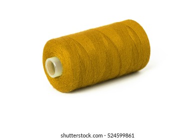 Close up detail still life of a dark yellow spool of thread isolated on white background copy space - concept fashion DIY clothing sewing handicraft design handmade textile tradition