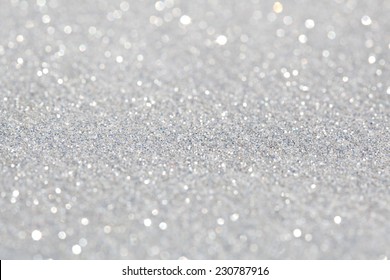 Close up detail view of silver glitter background shining and reflecting light and showing stars. Full frame glitter texture. Party, celebration, abstract and festive background textures.