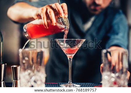 Close up details of barman pouring vodka cosmopolitan cocktail in martini glass