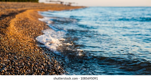 Close up details of beach sands, small pebbles shining in the sunrise on the morning beach of the mediterranean island, Cephalonia, Greece