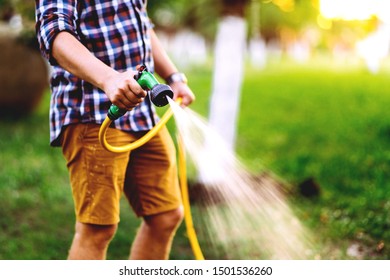 Close Up Details Of Gardener Using Hosepipe Watering The Lawn, Grass And Plants