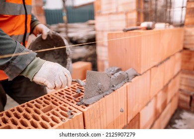 Close up details of industrial bricklayer installing bricks on industrial building, construction site - Shutterstock ID 2125907279