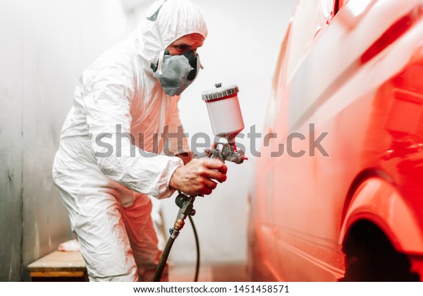 close up details of industrial\
worker, mechanic engineer using a paint gun and painting a\
car