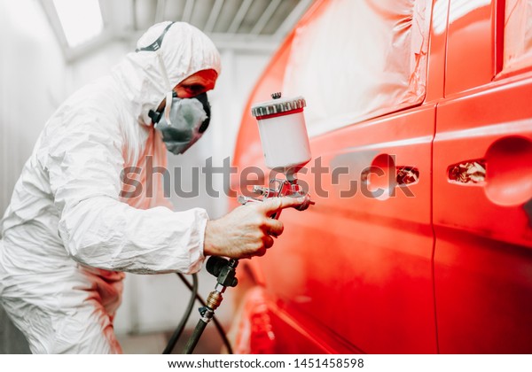 Close\
up details of mechanic worker, painting a red\
car